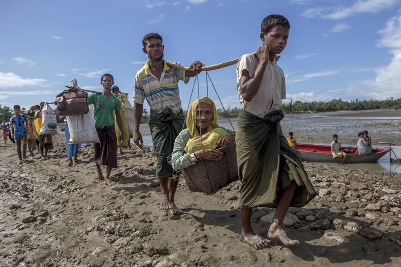 Rohingya Muslims, who crossed over from Myanmar into Bangladesh, carry an elderly woman in a basket and walk towards a refugee camp in Shah Porir Dwip, Bangladesh, Thursday, Sept. 14, 2017.