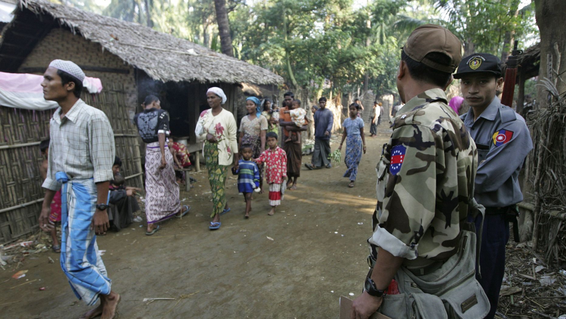 In this photo, Muslim refugees walk as Burma police officers stand guard at Sin Thet Maw relief camp in Pauktaw township, Rakhine state, western Burma. (AP)