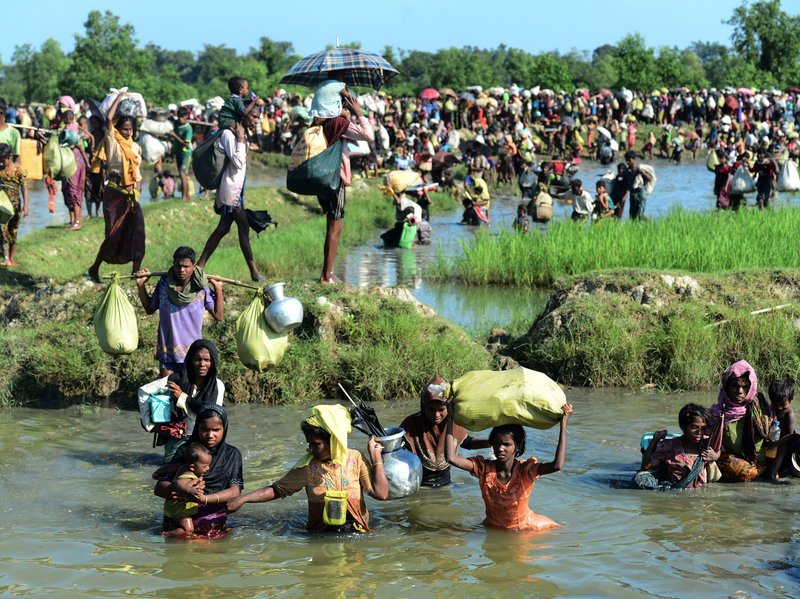 Rohingya refugees walk through a shallow canal after crossing the Naf River to reach Bangladesh