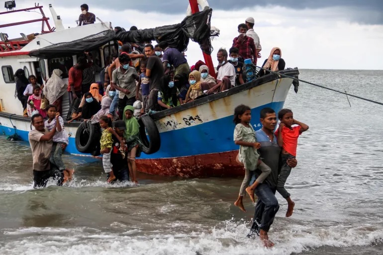 Locals evacuate Rohingya refugees from a boat that came ashore on the north coast of Indonesia's Sumatra island in June 2020. The UNHCR says the journey across the Andaman Sea last year was deadlier than ever before [Rahmad/Antara Foto via Reuters]