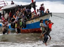 Locals evacuate Rohingya refugees from a boat that came ashore on the north coast of Indonesia's Sumatra island in June 2020. The UNHCR says the journey across the Andaman Sea last year was deadlier than ever before [Rahmad/Antara Foto via Reuters]